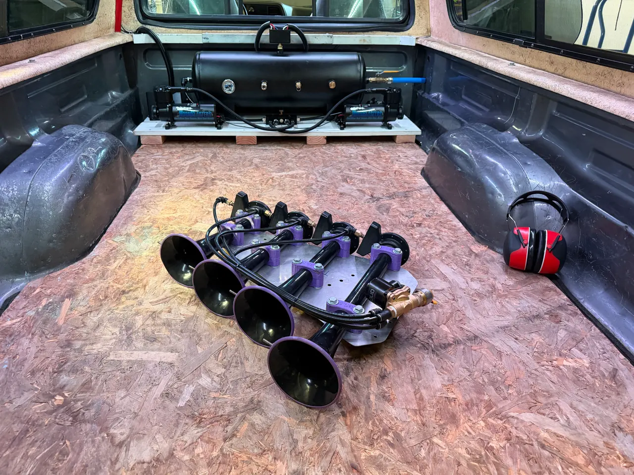 In the bed, with the 8-gallon tank and dual compressors behind
